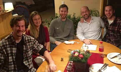 Five people sitting around a dinner table smiling