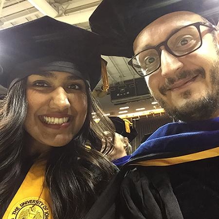 Two people in graduation caps smiling