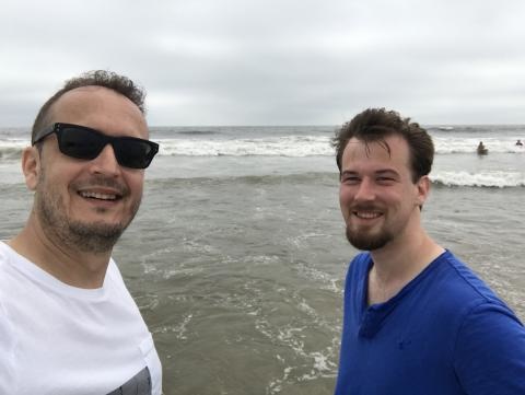 Two people taking a selfie while standing on the shore of a beach
