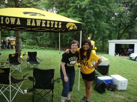 Two people smiling outside under an Iowa Hawkeyes tent roof