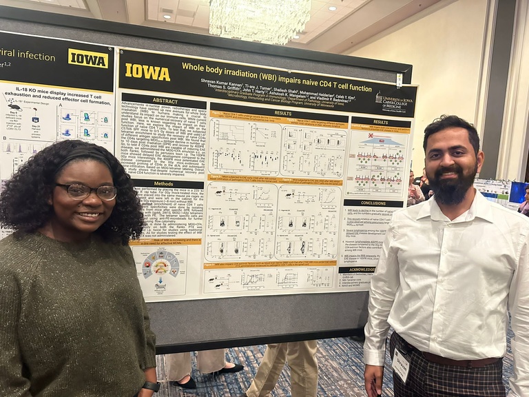 Two people smiling in front of a research poster