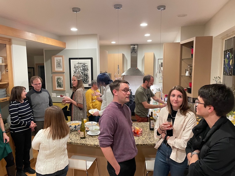 Many people in a kitchen area talking and drinking