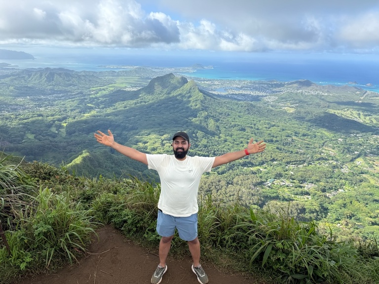 A person with arms outstretched over a scenic view of mountains
