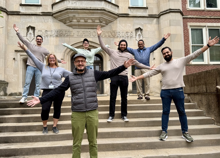 Badovinac Lab members standing on the stairs of the med lab building, smiling with arms outstretched