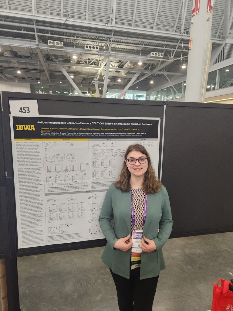 A person in front of a presentation poster, smiling